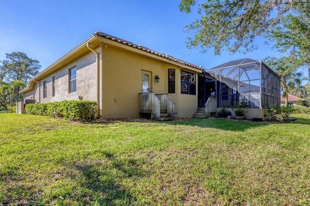 rear view of property featuring a yard and glass enclosure