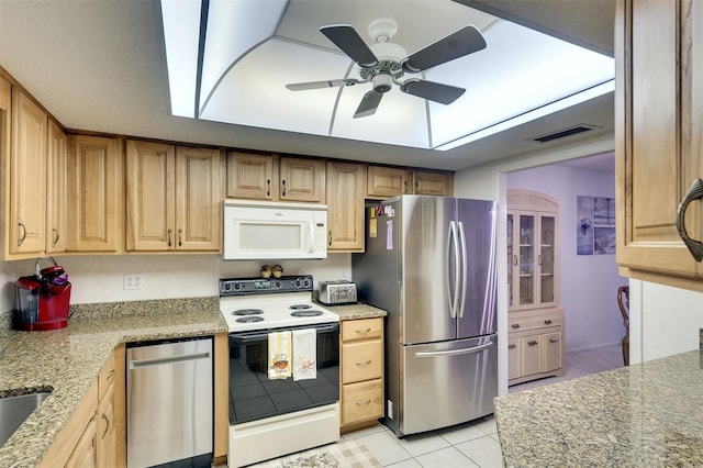 kitchen with appliances with stainless steel finishes, light stone counters, ceiling fan, and light tile patterned flooring