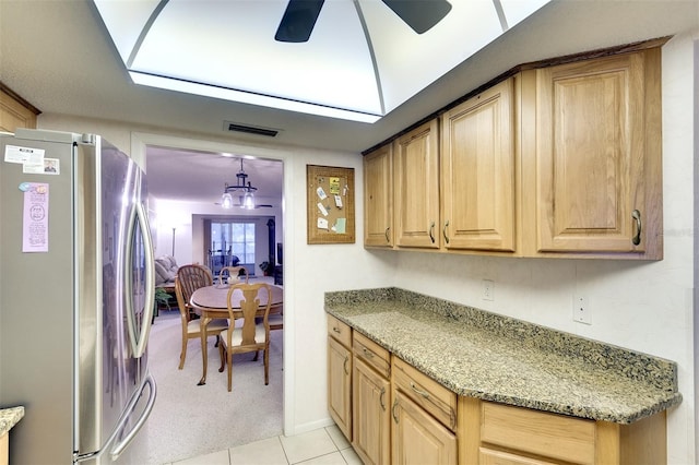 kitchen featuring light carpet, stone counters, ceiling fan, decorative light fixtures, and stainless steel refrigerator