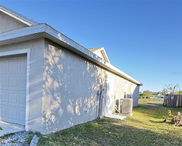 4042 Kingsfield Dr, Parrish, FL 34219 - view of side of home with central air condition unit, stucco siding, a yard, and a garage