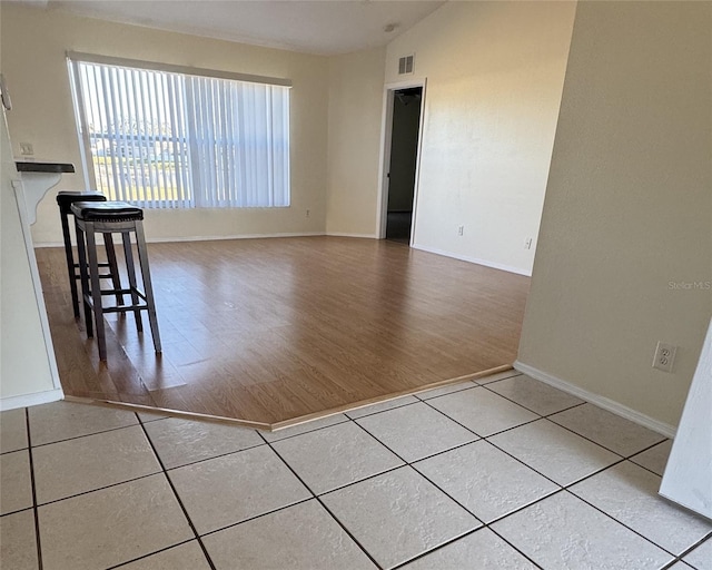 empty room with light wood-type flooring, a fireplace, and vaulted ceiling