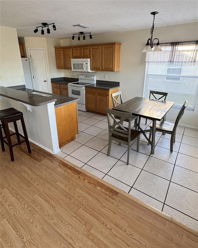 kitchen featuring light tile patterned floors, white appliances, a textured ceiling, and hanging light fixtures