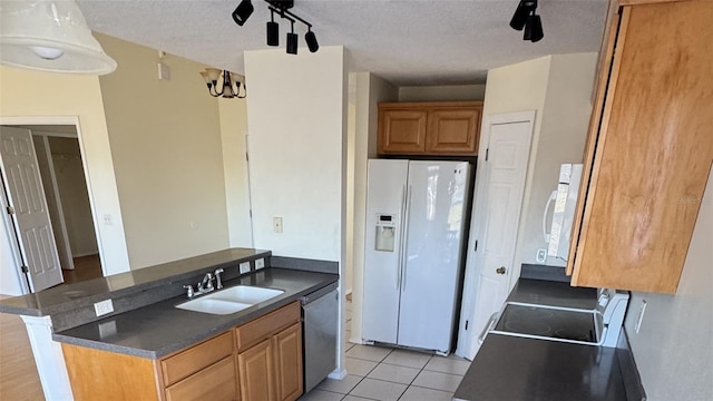 kitchen featuring sink, stainless steel dishwasher, white fridge with ice dispenser, light tile patterned floors, and a textured ceiling