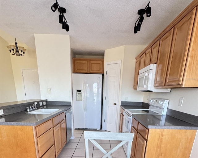 kitchen with a textured ceiling, white appliances, rail lighting, and a notable chandelier