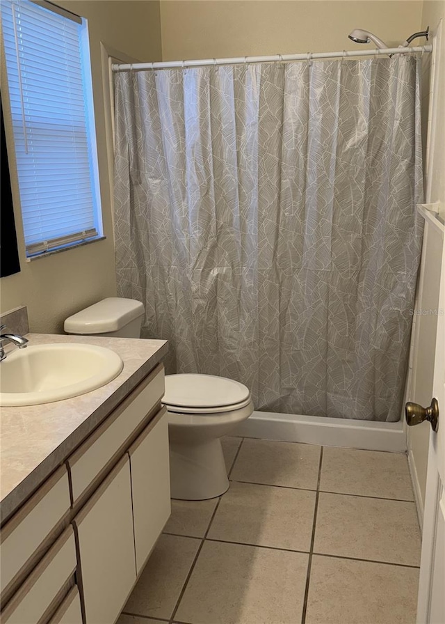 bathroom featuring tile patterned floors, vanity, toilet, and walk in shower