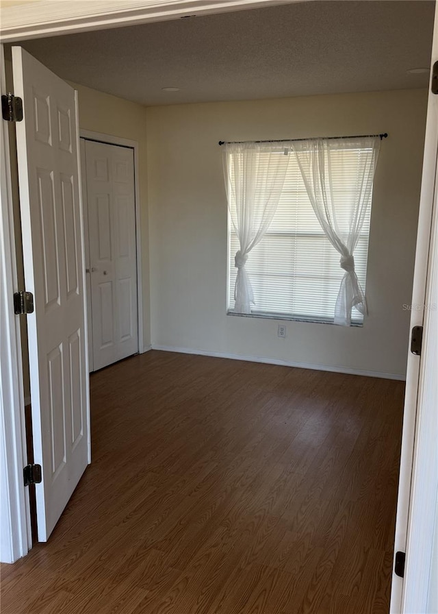 unfurnished room with dark hardwood / wood-style floors and a textured ceiling