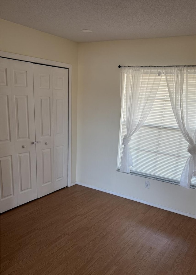 4042 Kingsfield Dr, Parrish, FL 34219 - unfurnished bedroom with dark wood finished floors, a closet, baseboards, and a textured ceiling