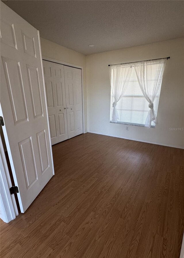 4042 Kingsfield Dr, Parrish, FL 34219 - unfurnished bedroom with dark wood-type flooring, a textured ceiling, and a closet