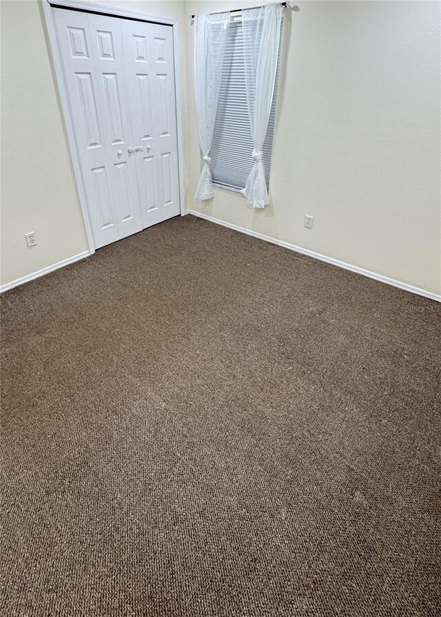 4042 Kingsfield Dr, Parrish, FL 34219 - unfurnished bedroom with dark carpet, baseboards, and a closet
