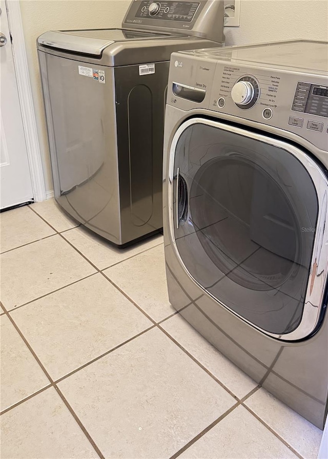 laundry area featuring light tile patterned flooring and washing machine and dryer