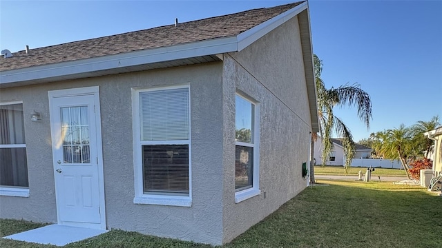 4042 Kingsfield Dr, Parrish, FL 34219 - view of side of property featuring stucco siding, a lawn, and roof with shingles