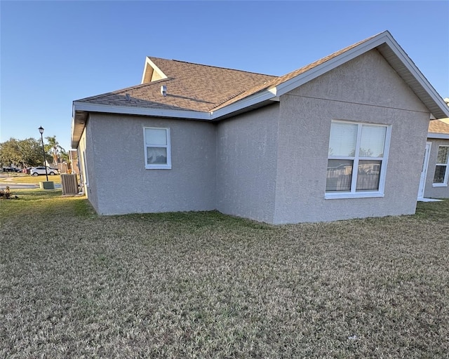 4042 Kingsfield Dr, Parrish, FL 34219 - view of side of property featuring stucco siding, a yard, roof with shingles, and central air condition unit