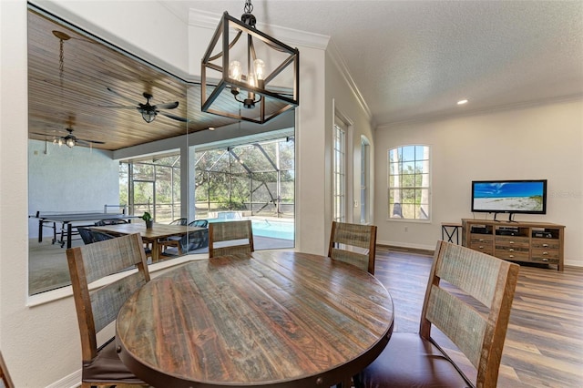 dining space with ceiling fan with notable chandelier, hardwood / wood-style floors, a textured ceiling, and crown molding