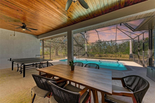 patio terrace at dusk featuring glass enclosure and ceiling fan