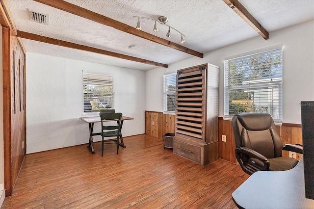 office space featuring beam ceiling, wood walls, wood-type flooring, and a textured ceiling