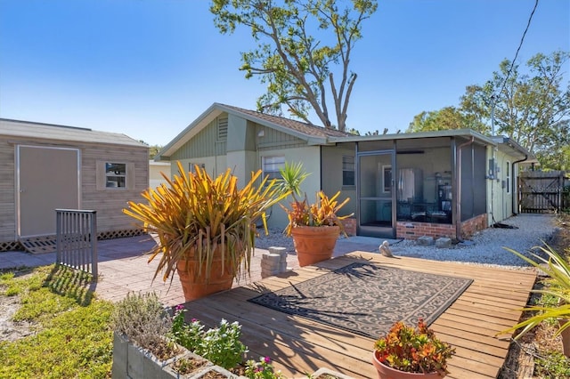 rear view of property featuring a sunroom and a deck