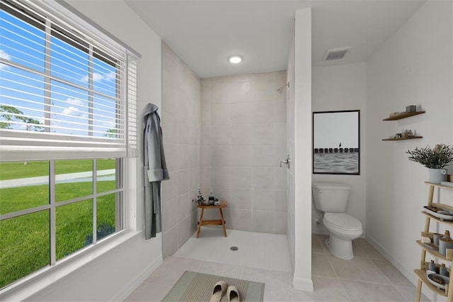 bathroom with tile patterned floors, toilet, and a tile shower