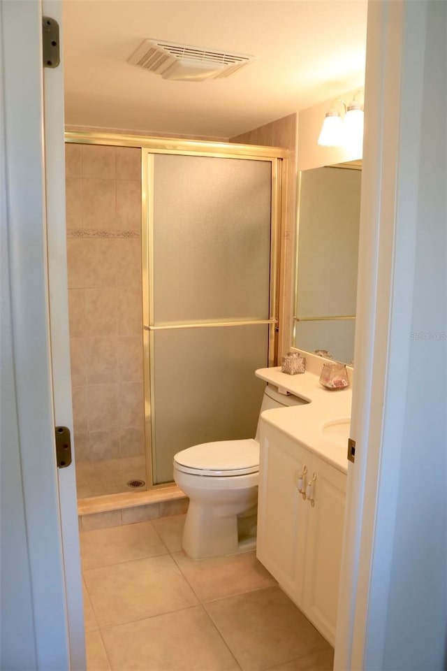 bathroom with tile patterned floors, vanity, toilet, and a shower with door