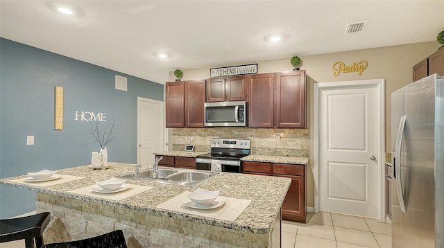 kitchen featuring decorative backsplash, appliances with stainless steel finishes, a kitchen island with sink, sink, and light tile patterned flooring