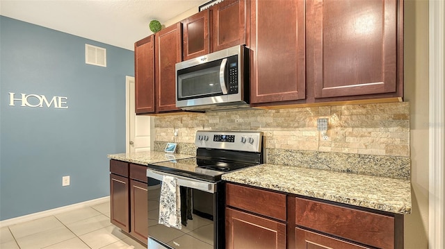 kitchen with light stone countertops, light tile patterned floors, stainless steel appliances, and decorative backsplash