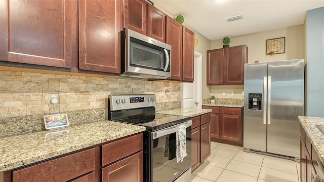 kitchen featuring backsplash, light tile patterned flooring, light stone countertops, and stainless steel appliances