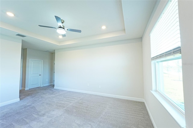 carpeted empty room featuring ceiling fan and a tray ceiling