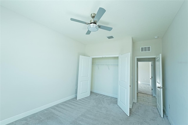 unfurnished bedroom featuring ceiling fan, a closet, and light carpet