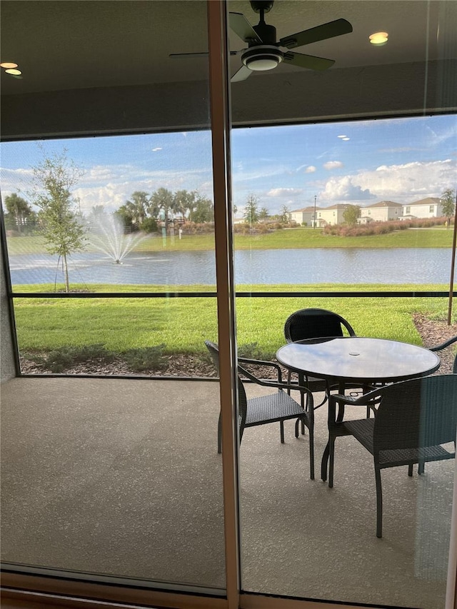 sunroom / solarium featuring ceiling fan and a water view