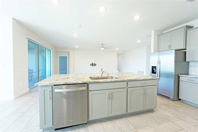 kitchen featuring appliances with stainless steel finishes, a center island with sink, gray cabinets, and ceiling fan