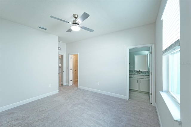 unfurnished bedroom with ensuite bathroom, ceiling fan, light carpet, and multiple windows