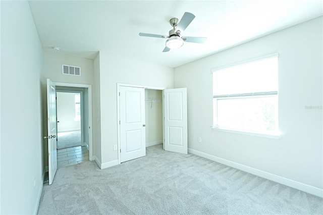 unfurnished bedroom featuring ceiling fan, a closet, and light colored carpet