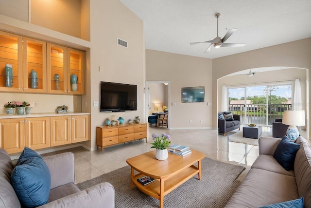 tiled living room with ceiling fan and high vaulted ceiling