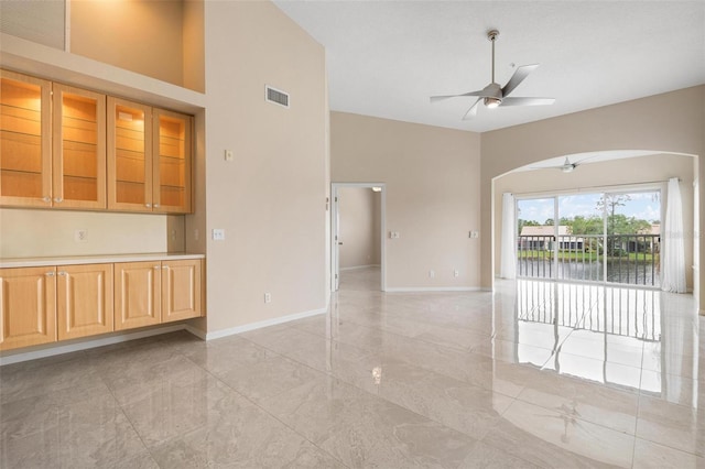 unfurnished room with a towering ceiling, a water view, and ceiling fan