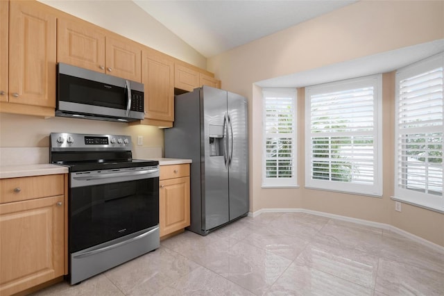 kitchen featuring lofted ceiling, stainless steel appliances, and light brown cabinetry