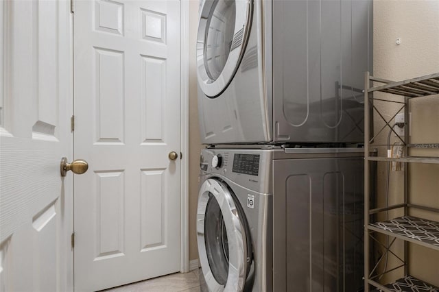 clothes washing area featuring light tile patterned flooring and stacked washer and dryer