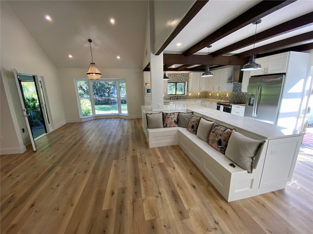 unfurnished living room featuring beamed ceiling, light wood-type flooring, and high vaulted ceiling