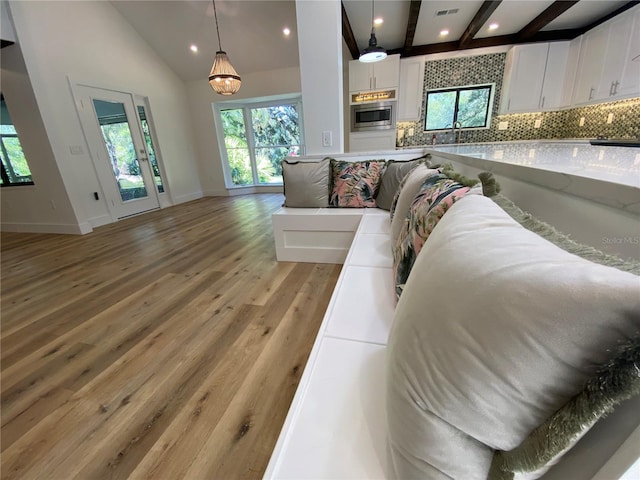 living room featuring vaulted ceiling with beams, plenty of natural light, and light wood-type flooring