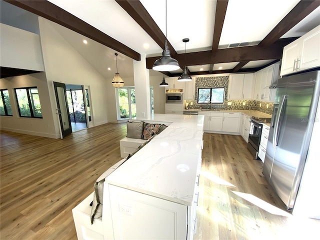 kitchen with a center island, white cabinetry, hanging light fixtures, and appliances with stainless steel finishes