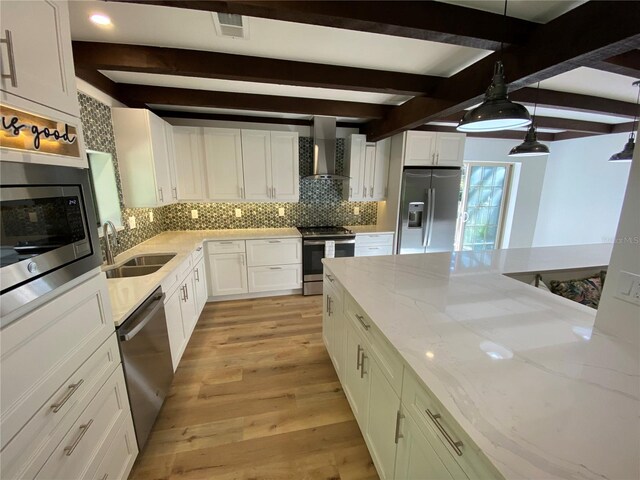 kitchen with sink, wall chimney exhaust hood, stainless steel appliances, beamed ceiling, and decorative backsplash