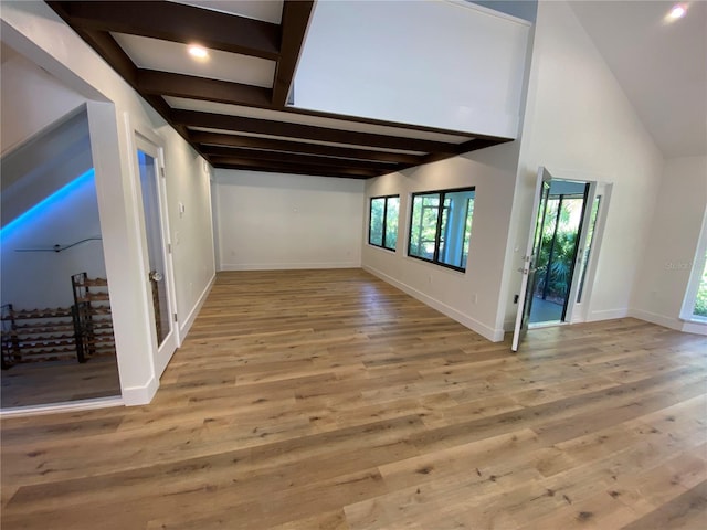 empty room with beamed ceiling and light wood-type flooring