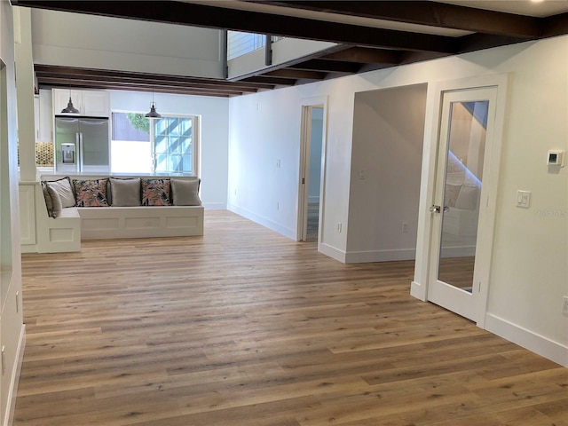 unfurnished living room featuring beamed ceiling and light hardwood / wood-style floors