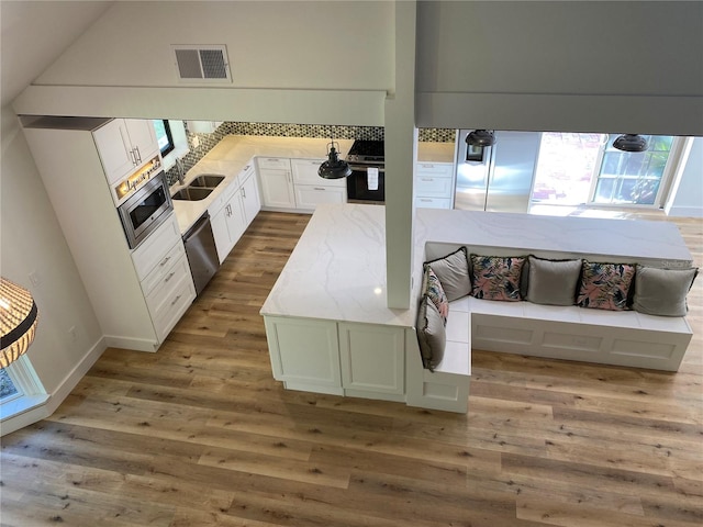 kitchen featuring light stone countertops, stainless steel appliances, sink, hardwood / wood-style flooring, and white cabinetry