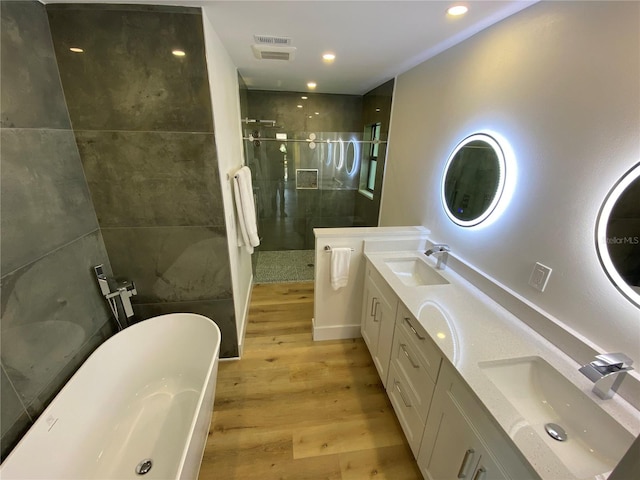 bathroom with hardwood / wood-style floors, vanity, and plus walk in shower