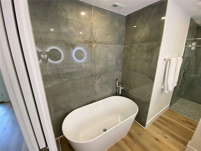 bathroom featuring hardwood / wood-style flooring, separate shower and tub, and tile walls