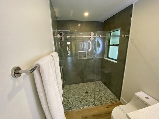 bathroom with hardwood / wood-style floors, toilet, and an enclosed shower