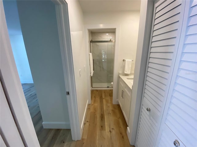 bathroom with toilet, a shower with door, vanity, and hardwood / wood-style flooring