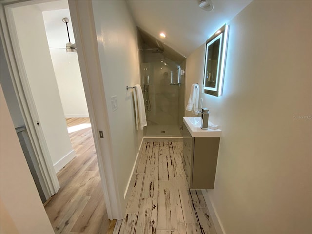 bathroom featuring hardwood / wood-style flooring, vanity, lofted ceiling, and walk in shower