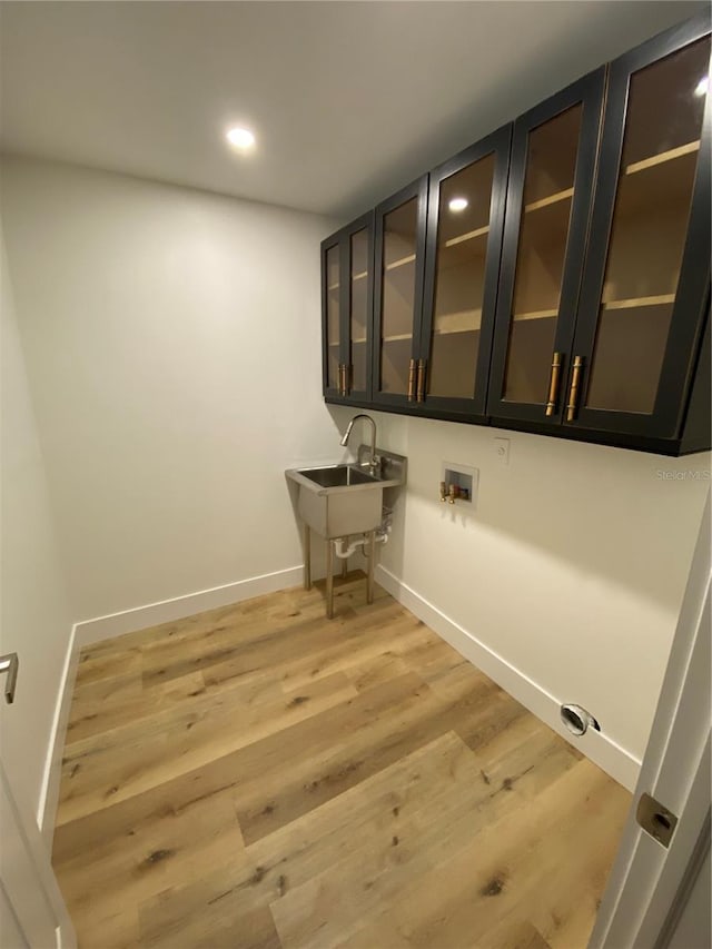 laundry area with cabinets, light wood-type flooring, sink, and hookup for a washing machine