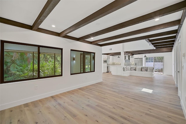 unfurnished living room featuring beamed ceiling and light hardwood / wood-style flooring