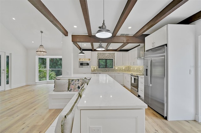 kitchen featuring white cabinetry, a healthy amount of sunlight, appliances with stainless steel finishes, and hanging light fixtures